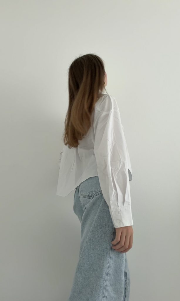 Frau kombiniert eine weißes Hemd mit heller Jeans für einen lässig-eleganten Look