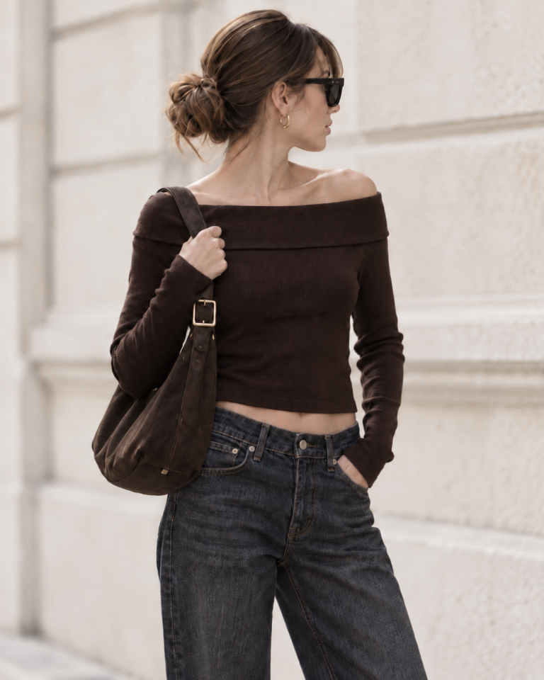 Detailaufnahme eines modernen Denim-Looks mit tief sitzender Jeans, braunem Off-Shoulder-Top und Schultertasche