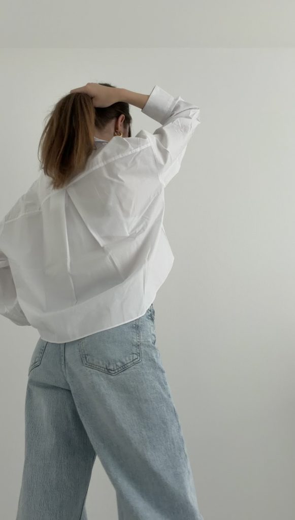 Frau von hinten in weißer Oversize-Bluse und heller Jeans – moderner Look im Stil Pariser Lebensart